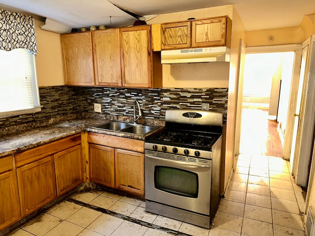 kitchen featuring tasteful backsplash, stainless steel range with gas stovetop, light tile flooring, and sink