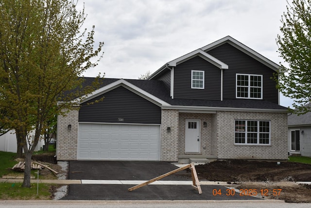 traditional-style home with brick siding, an attached garage, roof with shingles, and aphalt driveway