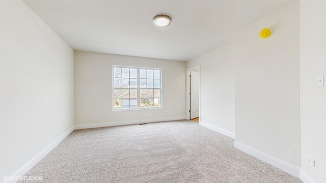 empty room featuring carpet floors, baseboards, and visible vents