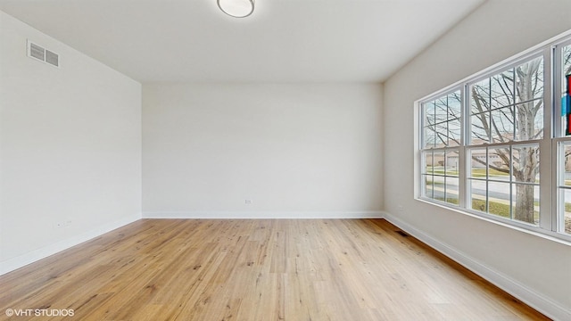 spare room with baseboards, wood finished floors, and visible vents