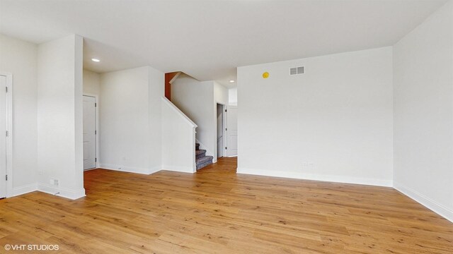 empty room with light wood-style floors, baseboards, and visible vents