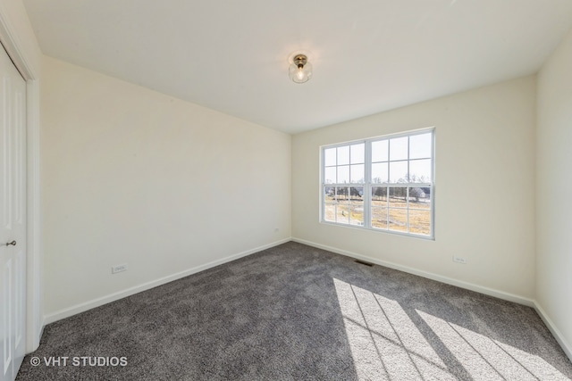 unfurnished room featuring dark colored carpet