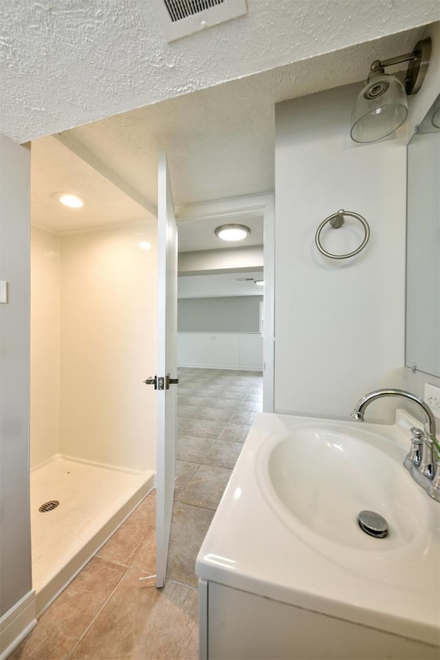 bathroom featuring walk in shower, a textured ceiling, vanity, and tile floors