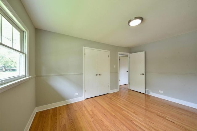 unfurnished bedroom with a closet and light wood-type flooring