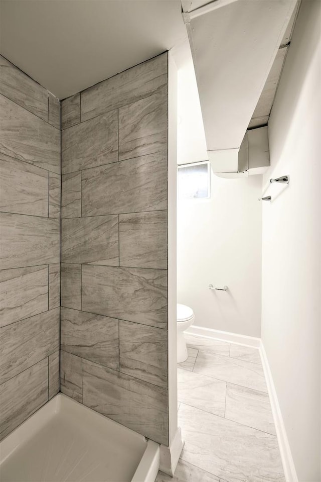 bathroom featuring toilet, tiled shower, and tile flooring