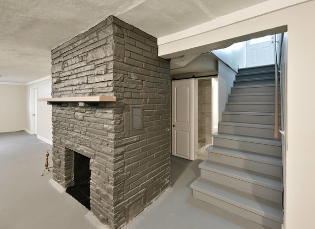 stairway featuring brick wall, crown molding, a fireplace, a barn door, and a textured ceiling