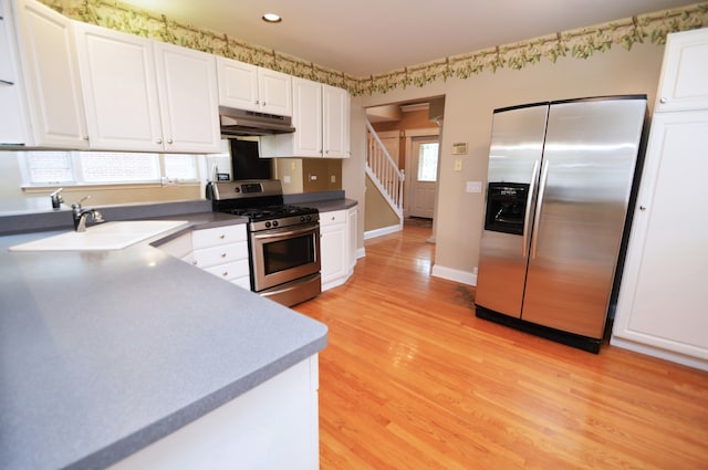 kitchen featuring appliances with stainless steel finishes, white cabinetry, sink, and light hardwood / wood-style floors