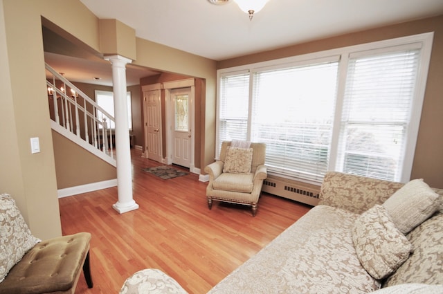 living room with baseboard heating, ornate columns, and hardwood / wood-style floors