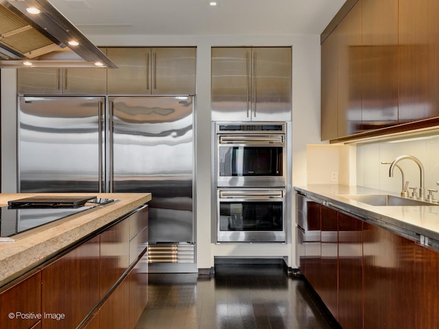 kitchen with cooktop, dark hardwood / wood-style floors, double oven, island range hood, and sink