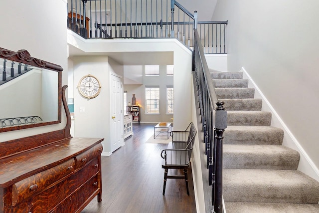 stairs with a towering ceiling, baseboards, and wood finished floors