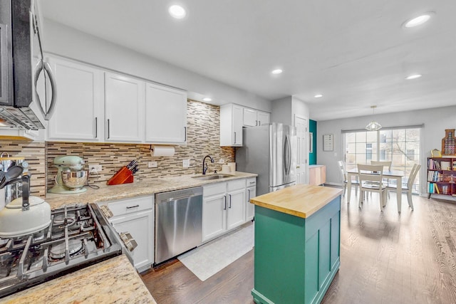 kitchen featuring butcher block countertops, appliances with stainless steel finishes, white cabinets, and a sink