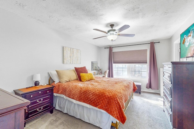 bedroom with a textured ceiling, a ceiling fan, and light colored carpet