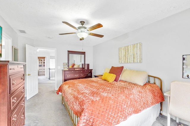 bedroom with visible vents, ceiling fan, light carpet, and a textured ceiling