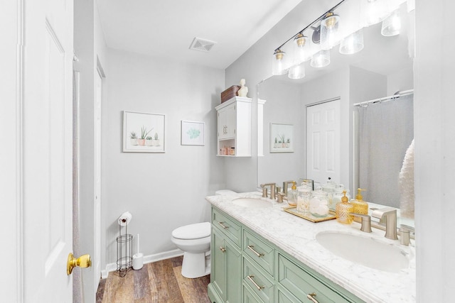 bathroom with toilet, wood finished floors, a sink, and visible vents