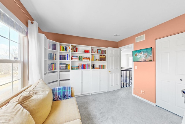 living area featuring a wealth of natural light, baseboards, visible vents, and carpet flooring