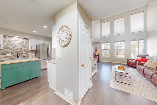 kitchen featuring visible vents, decorative backsplash, dark wood-style floors, open floor plan, and freestanding refrigerator