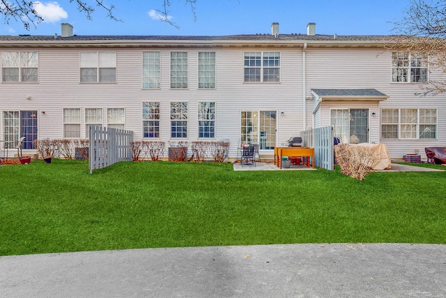 rear view of property featuring a chimney, a patio, and a yard