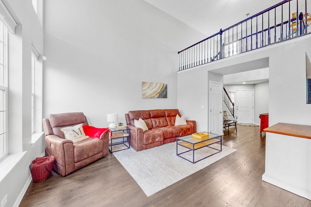 living area featuring stairway, wood finished floors, a towering ceiling, and baseboards