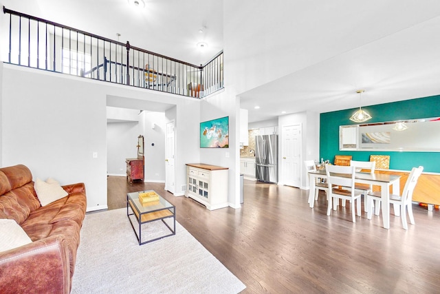 living room with a high ceiling, baseboards, and wood finished floors