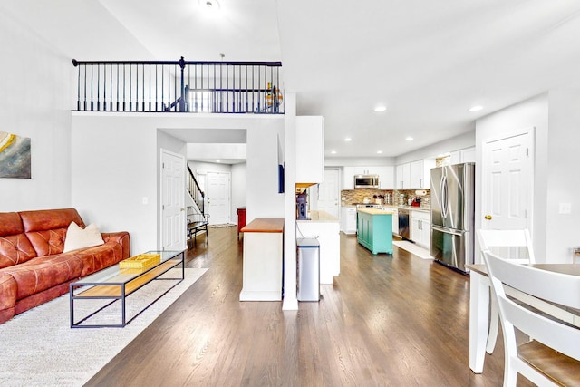 kitchen featuring dark wood-type flooring, white cabinets, open floor plan, light countertops, and appliances with stainless steel finishes