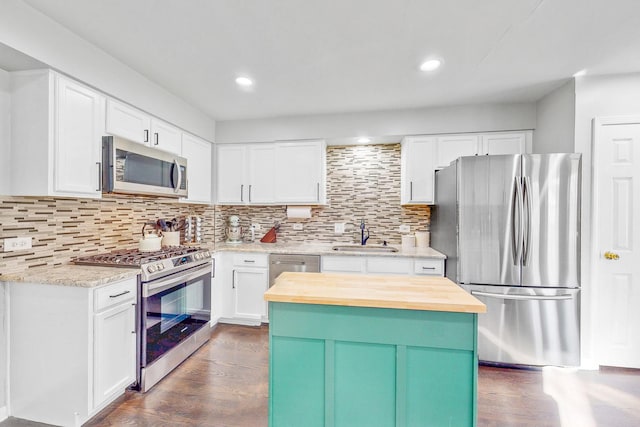 kitchen featuring tasteful backsplash, dark wood-style floors, butcher block counters, stainless steel appliances, and a sink