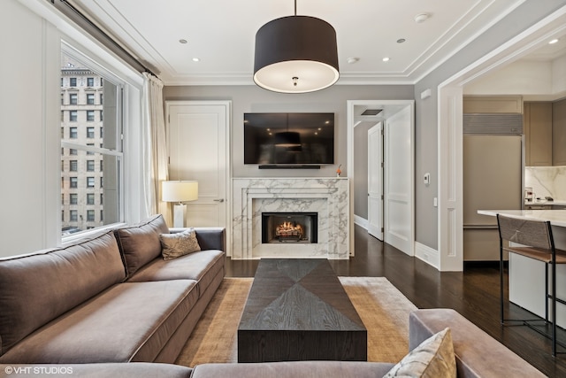 living room with a wealth of natural light, a premium fireplace, dark hardwood / wood-style flooring, and ornamental molding