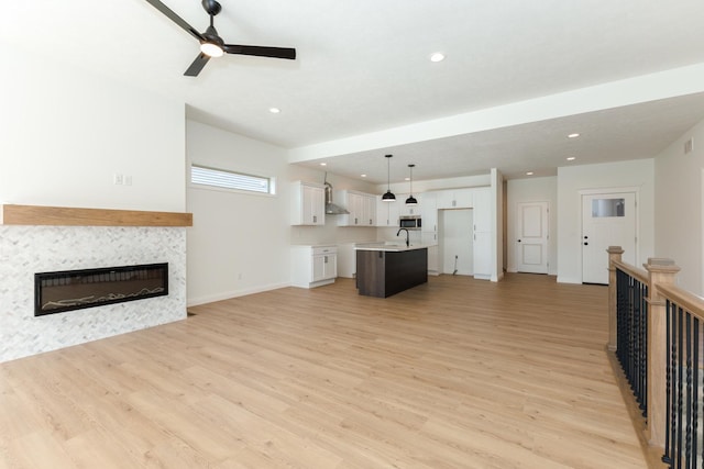 unfurnished living room featuring light wood-type flooring, ceiling fan, and sink