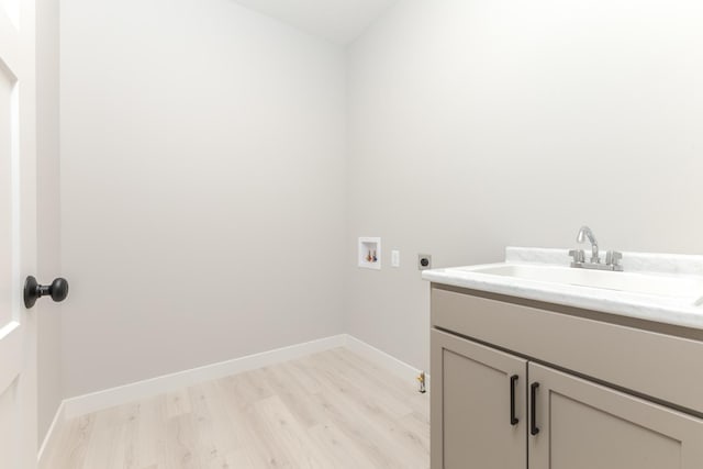 laundry area featuring sink, cabinets, hookup for an electric dryer, light hardwood / wood-style flooring, and hookup for a washing machine