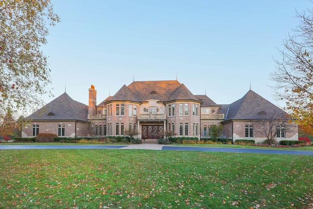 french country home with a balcony and a front lawn