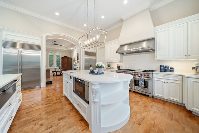 kitchen featuring white cabinetry, wall chimney range hood, and premium appliances