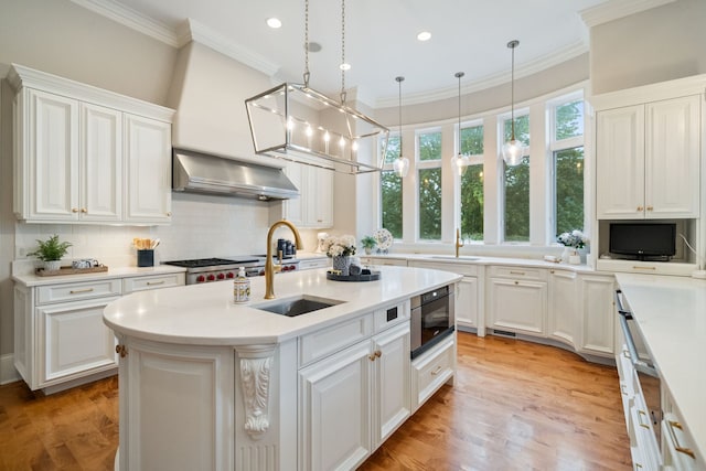 kitchen featuring white cabinets, pendant lighting, a kitchen island with sink, and wall chimney exhaust hood