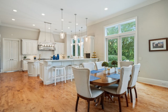 dining room featuring light hardwood / wood-style floors, ornamental molding, and sink