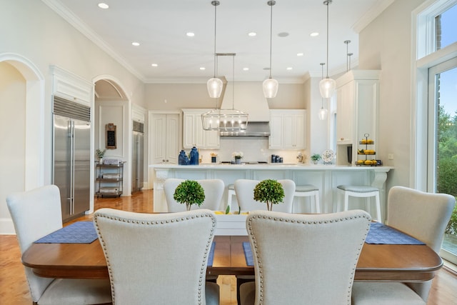 dining space with crown molding and light hardwood / wood-style flooring