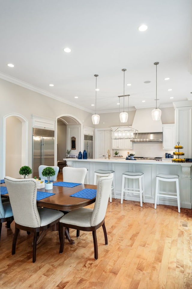 dining space featuring light wood-type flooring and ornamental molding