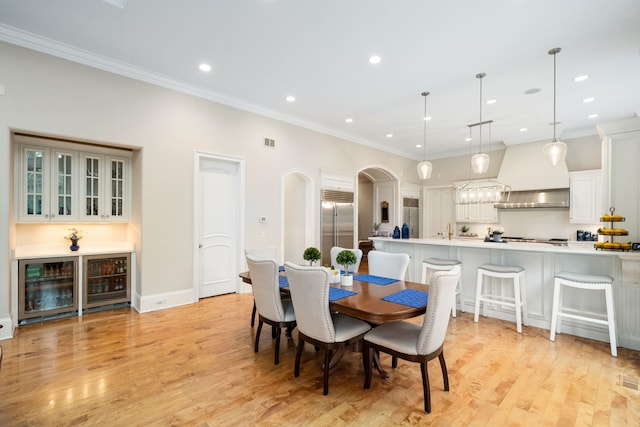 dining room featuring light hardwood / wood-style floors, ornamental molding, and wine cooler