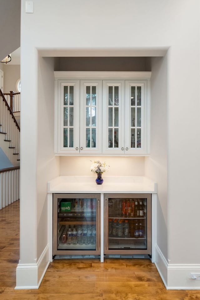 bar featuring wine cooler, white cabinetry, and light wood-type flooring