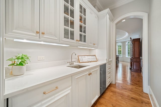 bar featuring sink, beverage cooler, ornamental molding, white cabinets, and light wood-type flooring