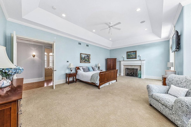 carpeted bedroom with a tray ceiling, ceiling fan, and crown molding