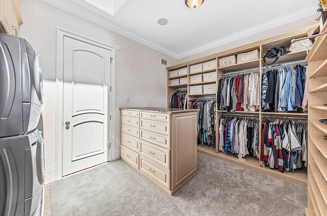 walk in closet with light colored carpet and stacked washer / drying machine