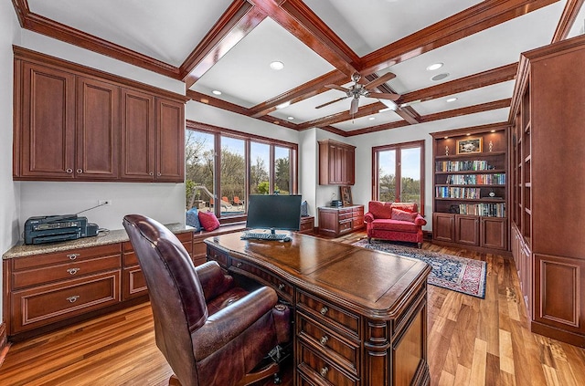 office space featuring coffered ceiling, crown molding, built in desk, light hardwood / wood-style flooring, and beamed ceiling