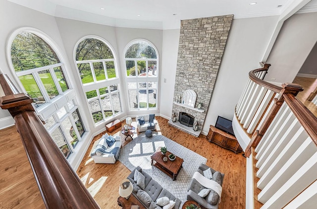 living room featuring a fireplace, light wood-type flooring, a wealth of natural light, and ornamental molding