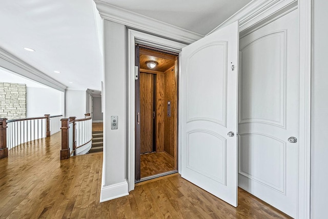 corridor with hardwood / wood-style flooring and ornamental molding