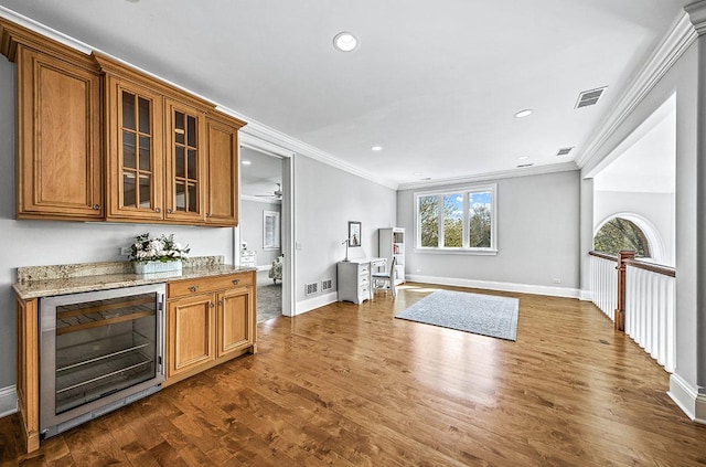 bar with dark hardwood / wood-style floors, light stone countertops, crown molding, and wine cooler