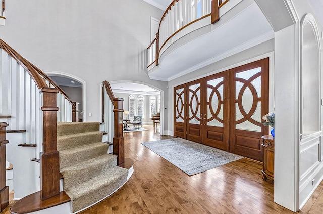 entryway with french doors, a towering ceiling, hardwood / wood-style flooring, and ornamental molding