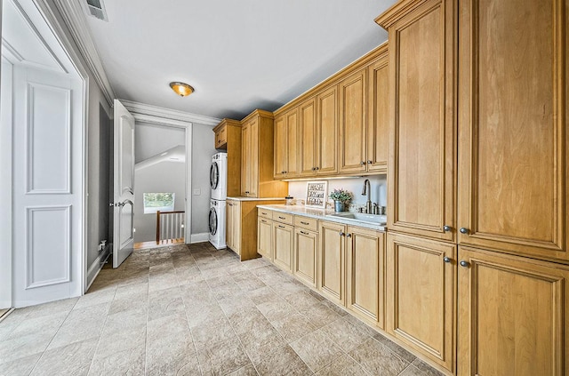 kitchen with sink, ornamental molding, and stacked washer and dryer