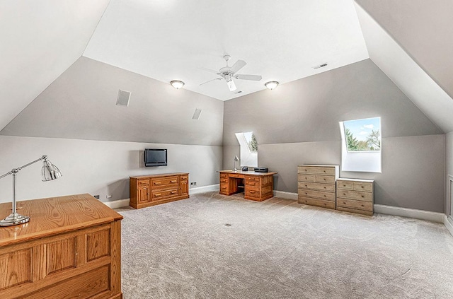 additional living space with ceiling fan, light colored carpet, and lofted ceiling with skylight