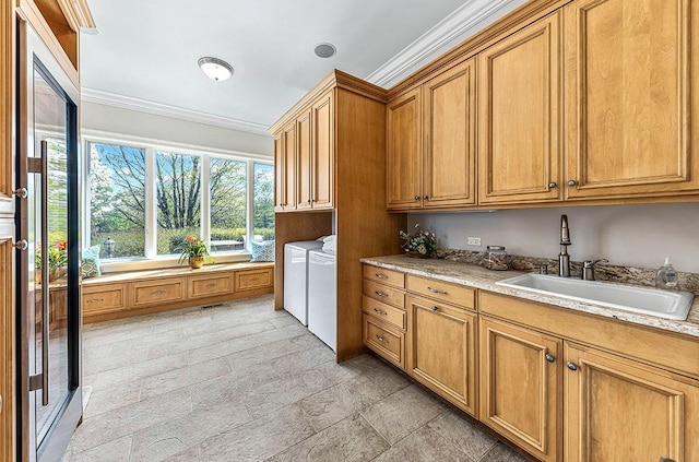 kitchen with light stone counters, washer and clothes dryer, ornamental molding, and sink