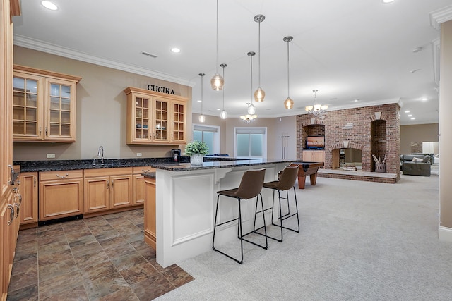 kitchen featuring carpet, a breakfast bar, light brown cabinets, pendant lighting, and a fireplace