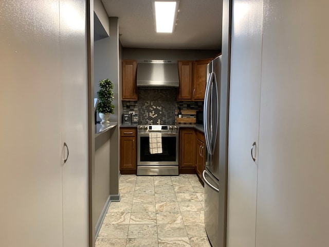 kitchen with backsplash, wall chimney exhaust hood, light tile flooring, and stainless steel appliances