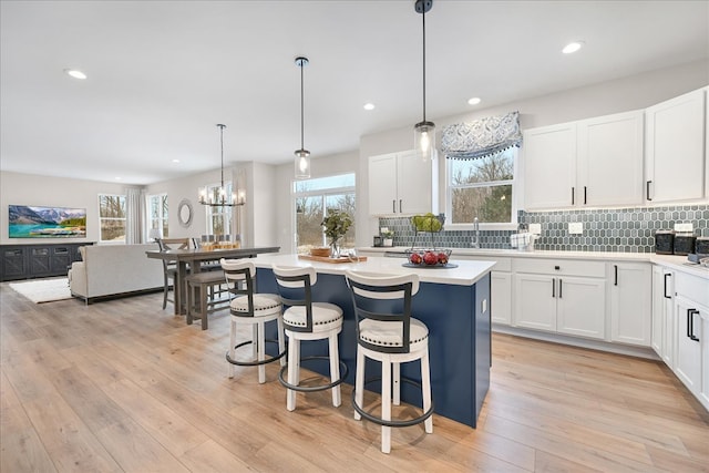 kitchen with white cabinets, light hardwood / wood-style flooring, a breakfast bar area, and pendant lighting